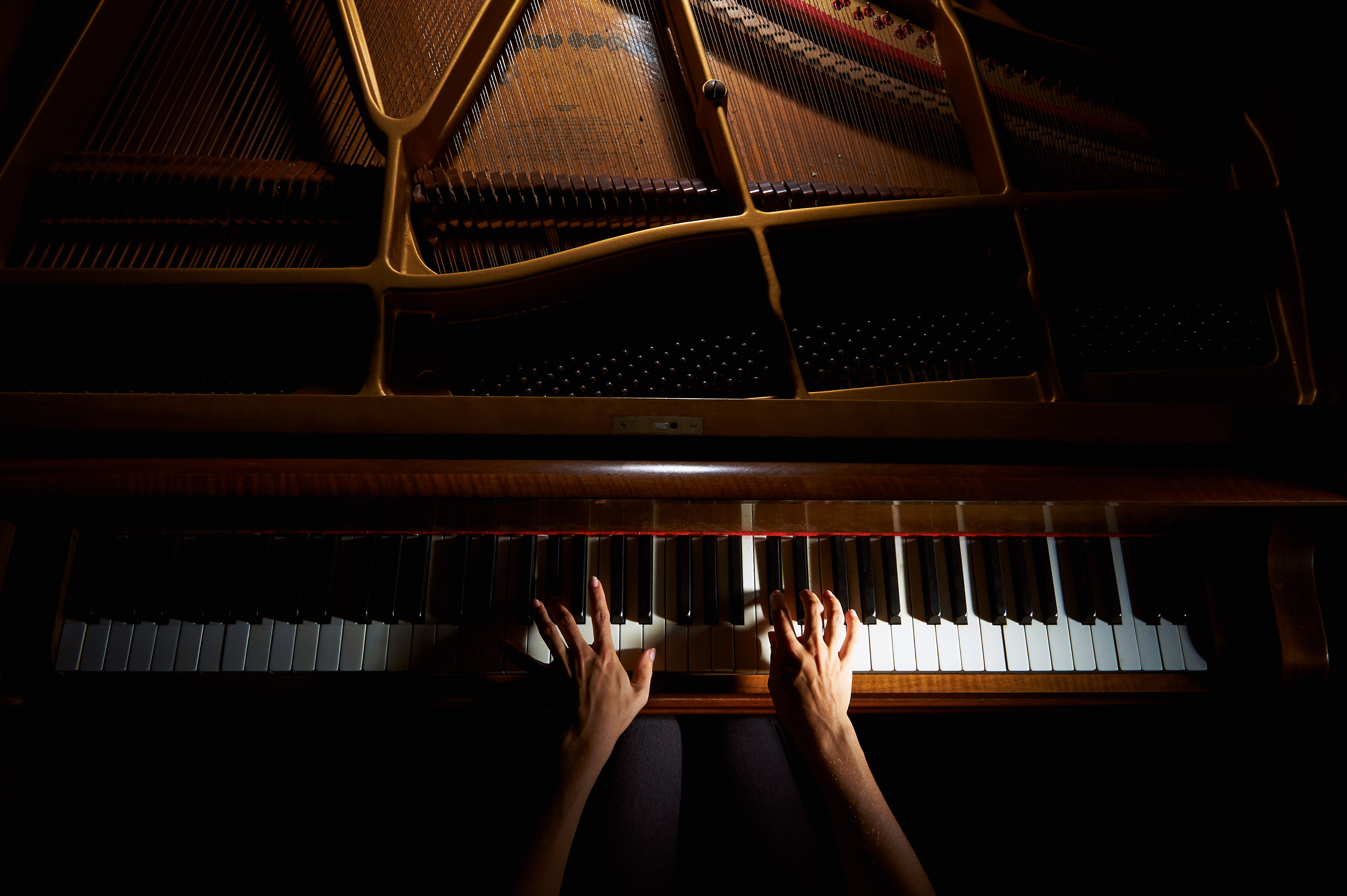 Woman's hands playing on the keyboard of the piano in night closeup